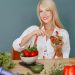 Blonde woman enjoying a fresh salad surrounded by vegetables, promoting healthy eating.