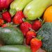 A vibrant selection of fresh fruits and vegetables including strawberries, avocado, and broccoli on a wooden table.